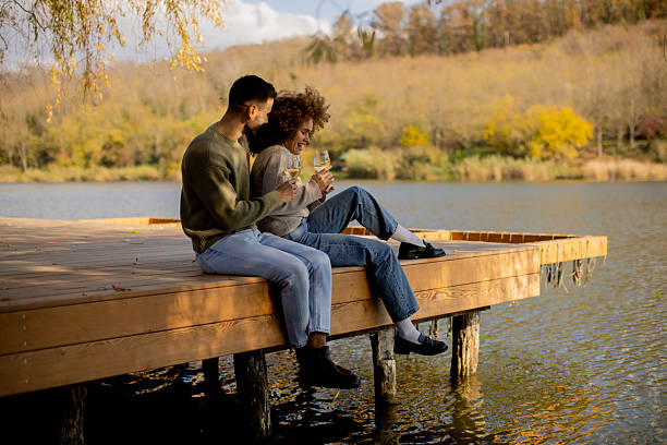 istock Couple enjoying drinks on a peaceful dock by the lake during autumn afternoon 2247643894
