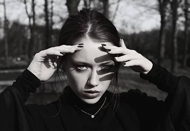 istock Elegant goth woman in a park shielding her eyes from the sun 2247644843