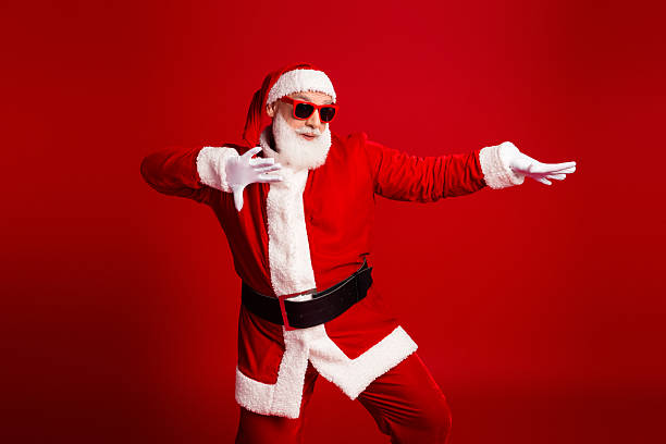 istock Santa in red suit with sunglass dancing in a bold red studio backdrop for festive holiday season celebration and family fun image 2247647304