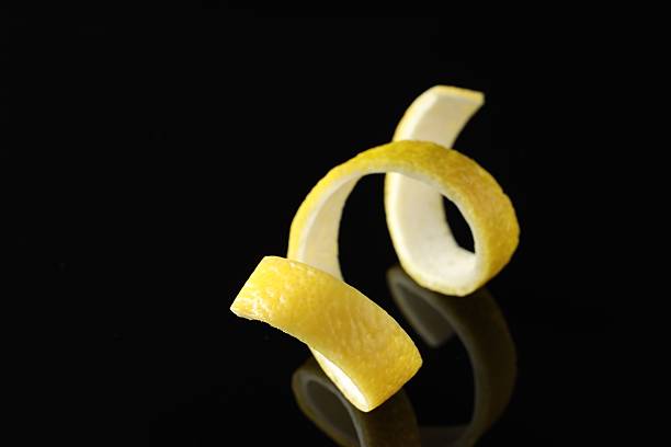 One curly lemon peel on black mirror surface, closeup
