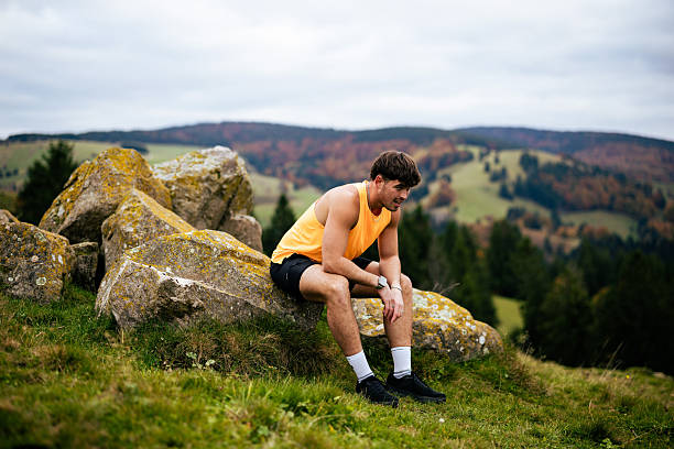 istock Trail runner pauses on rock in meadow on autumn day 2247648800
