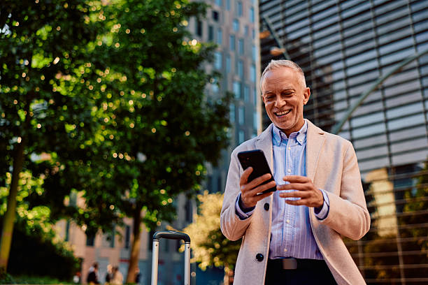 istock Senior businessman smiling using smartphone traveling city 2247649786