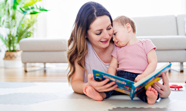 istock a happy mother with baby reading book. Baby is thinking 2247653100