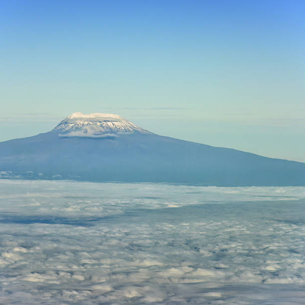 Mount Kilimanjaro, Africa's highest mountain, majestically rises above a breathtaking expanse of clouds, offering a captivating view from an airplane window
