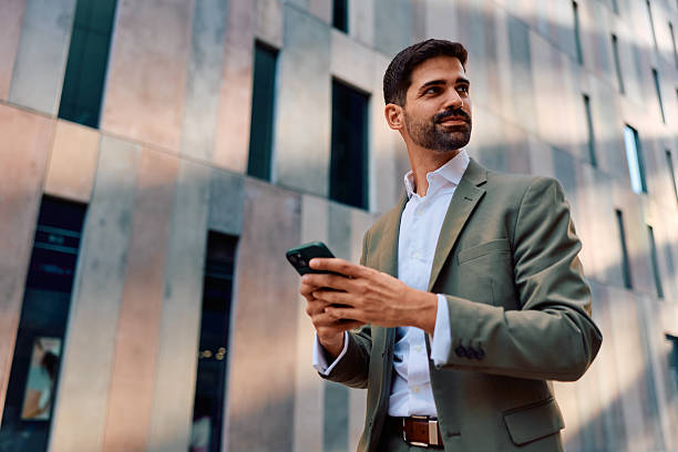 istock Businessman using smartphone looking away in city 2247653250