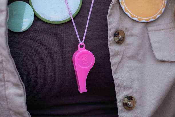 Pink whistle and activist pins on student clothing
