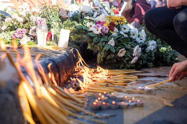 Mourners light candles and place flowers at a public memorial for remembrance