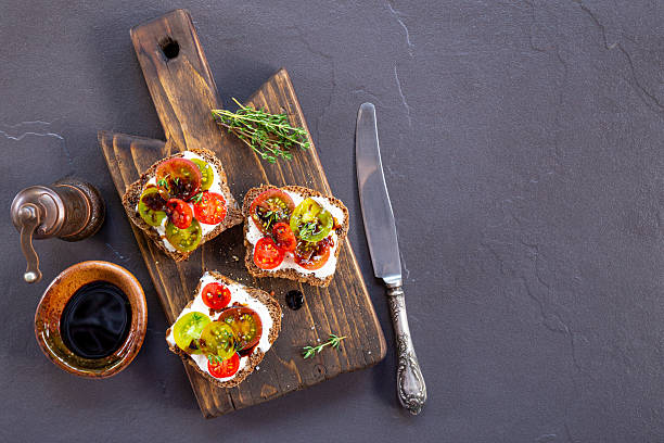 istock Bruschetta with cream cheese, cherry tomatoes on toasted bread on dark background top view copy space for text 2247655161