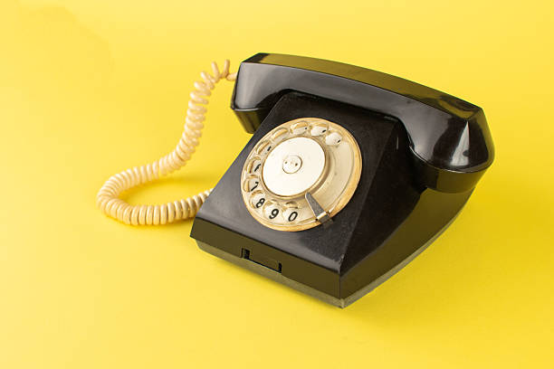 istock Vintage Black Rotary Phone on Vibrant Yellow Background Retro Communication Concept 2247655979