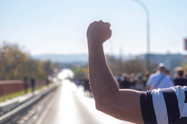 Demonstrator raising a clenched fist in the air during an outdoor protest