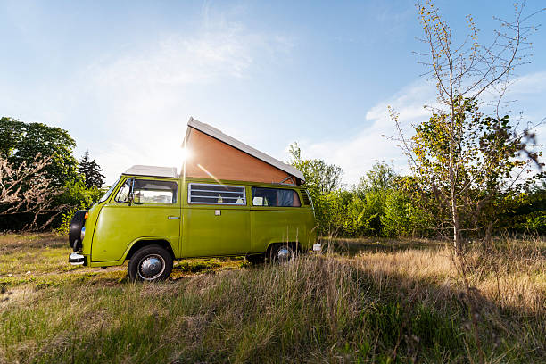 Germany - May 16, 2020: An old green Volkswagen VW Bus T2 stands on a meadow in the countryside. The special feature of this model is the pop-up roof, which provides extra comfort.