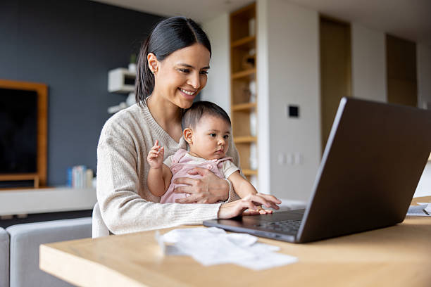 istock Happy mother working at home while carrying her baby 2247662520