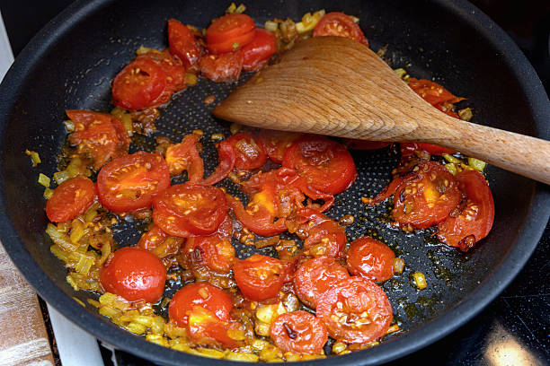 Healthy tomatoes and onion frying on stove