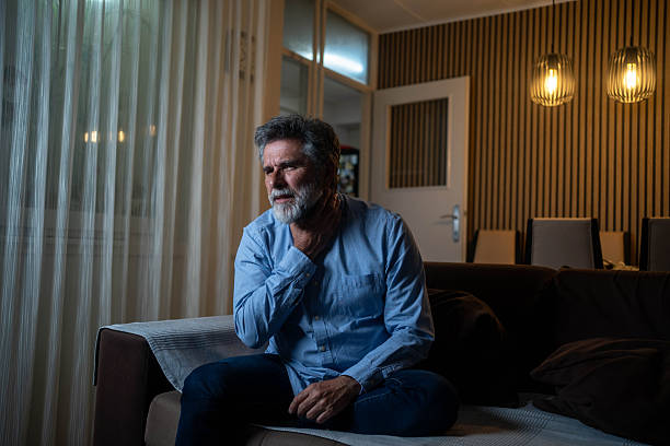 istock Sick man coughing on sofa with chest pain at home, possible illness. 2247664046