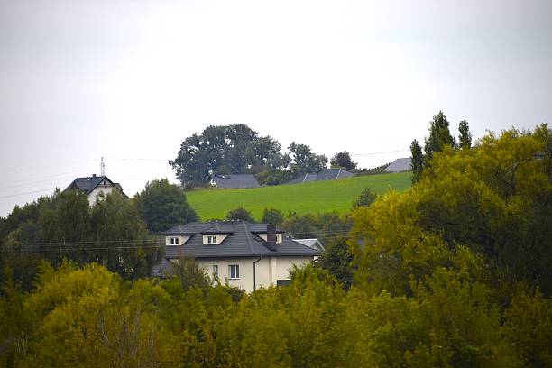 istock House behind autumn trees with hill and cloudy sky 2247664430