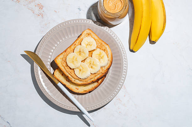istock Peanut butter sandwich and banana on a plate on a marble background 2247665401