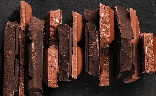 istock Assorted stacked chocolate bar pieces with rich textures and broken edges on dark background for premium confectionery branding and dessert advertising 2247667168