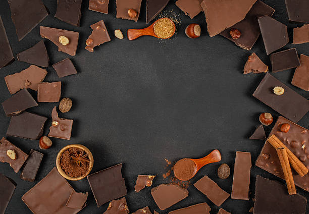 istock Chocolate pieces, nuts, cocoa powder and spices arranged around empty dark background with ample copy space for dessert menus, branding or advertising 2247667172