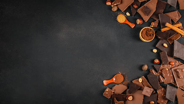 istock Assorted chocolate pieces with nuts and spices arranged on a dark textured background with generous copy space for branding, menus, or dessert advertising 2247667173