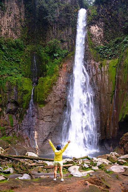 Young woman standing in front of El Toro waterfall which fall inside an extinct volcanic crater, Costa Rica