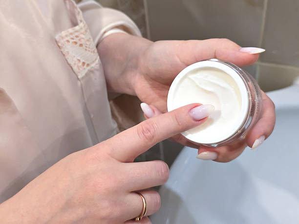 istock A woman's hand scoops cream from an open jar. 2247672340