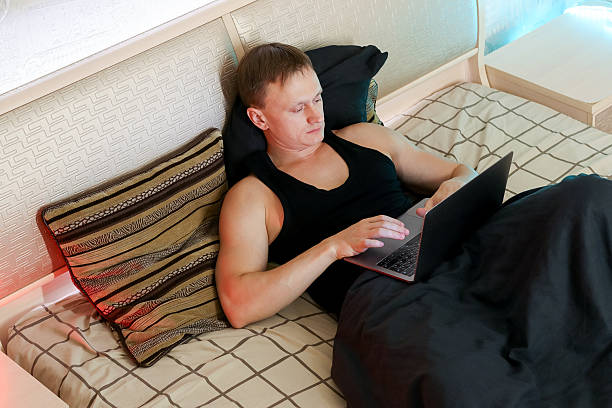 istock Relaxed man working on laptop in cozy bedroom with ambient lighting 2247672796