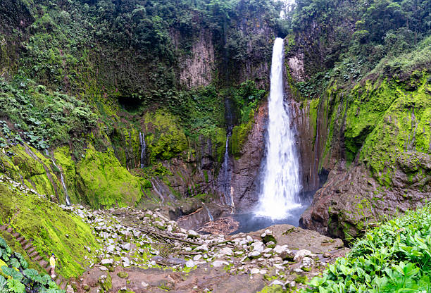 Young woman standing in front of El Toro waterfall which fall inside an extinct volcanic crater, Costa Rica
