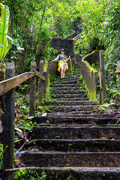 Young woman on the stairs of the trail to El Toro waterfall which falls inside an extinct volcanic crater, Costa Rica
