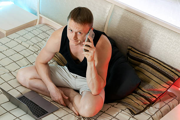 istock Intense man on call, hand resting on laptop from bed 2247676017
