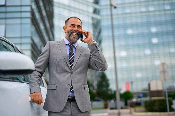 istock Smiling businessman talking on phone next to car 2247676136