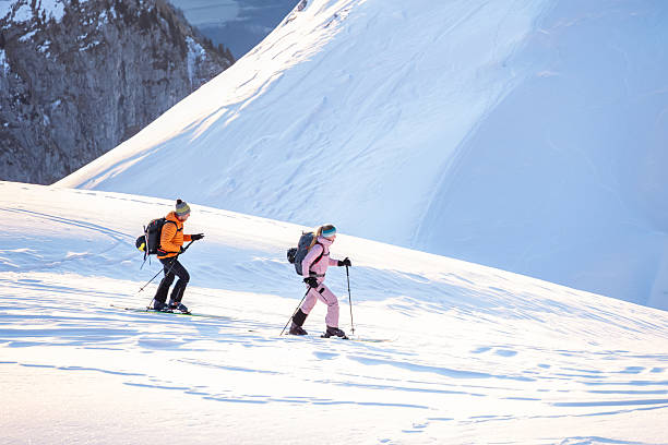 istock Two Skiers with Backpacks and Poles on a Snowy Mountain Slope 2247676687