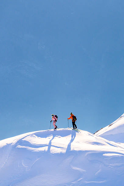 istock Two Skiers Ascending a Snowy Mountain Peak under a Clear Blue Sky 2247676702
