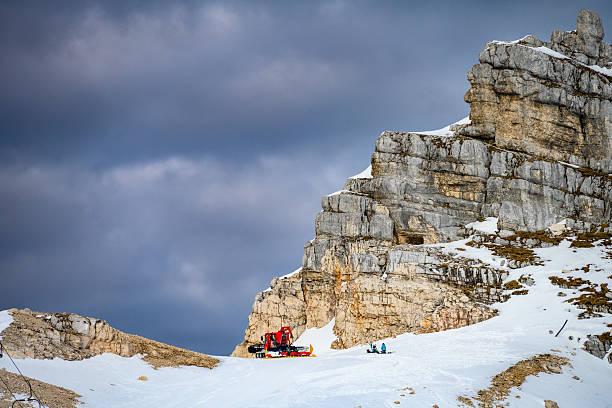 istock Red Snowmobile on Snowy Mountain Peak with Two Climbers in Blue Gear 2247677073