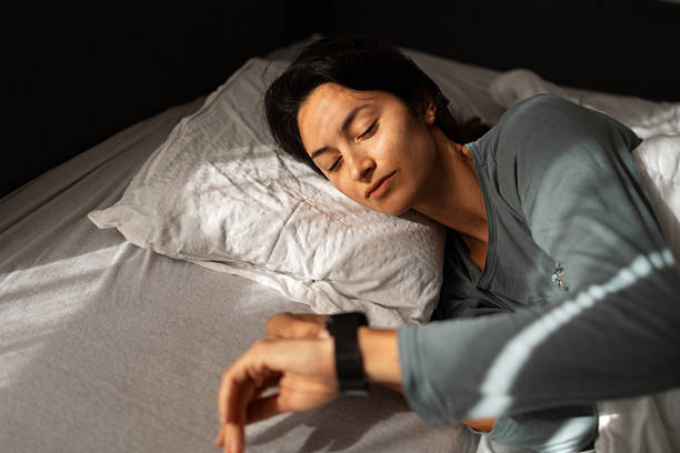 istock Young woman sleeping with sleep tracker smartwatch on wrist 2247677246