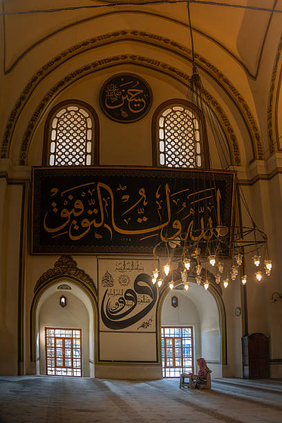 istock Woman praying inside uli camii, turkey mosque with islamic calligraphy 2247680523