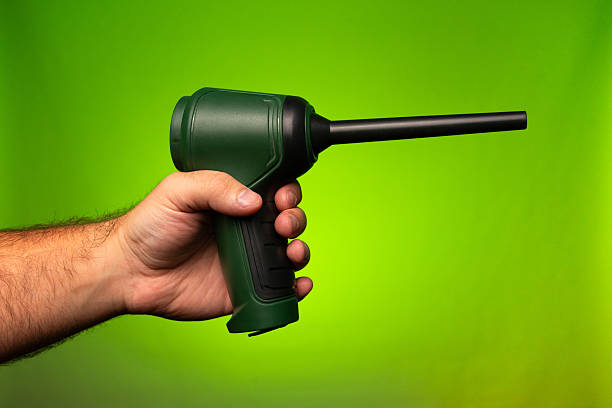 istock A man holding a small battery powered green vacuum. A man holding a small air compressor. A man holding a small air blower. Small vacuum. Small air blower. Small air compressor 2247681055