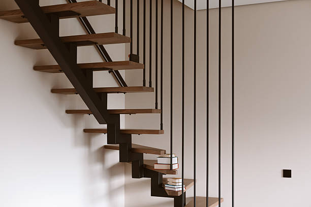 istock Modern floating staircase with wooden steps and black metal railings. A stack of books rests on the steps of this contemporary staircase, adding a touch of warmth to the minimalist design. Home space. 2247681842