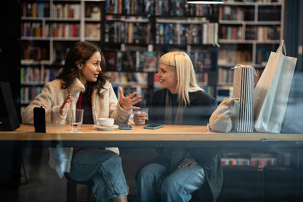 istock Two women friends having conversation in bookstore cafe 2247682000