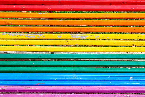 Stripes of bright colors adorn a bench in a park, inviting visitors to relax and enjoy the outdoors.