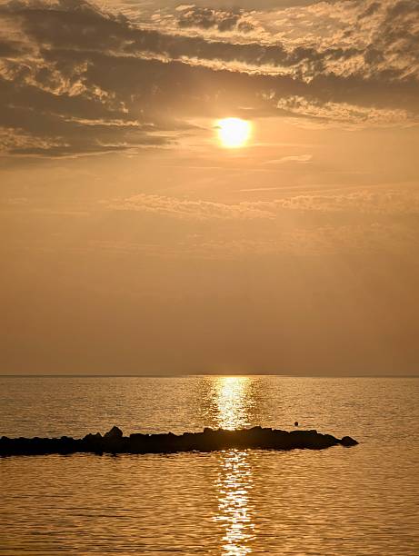 Warm golden sunset over tranquil sea with soft clouds and glowing reflections