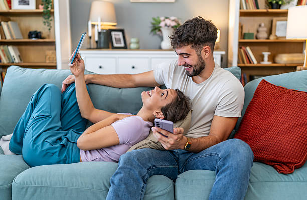 istock Happy young couple relaxing at home using smartphones 2247684784