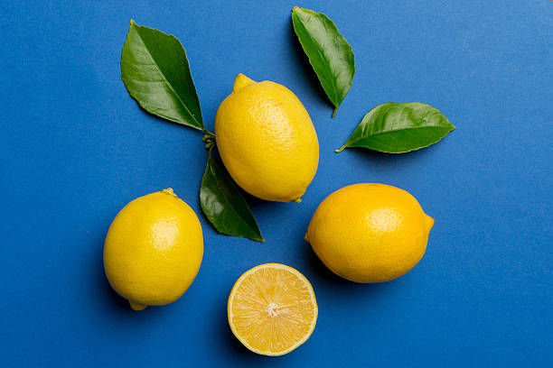istock Many fresh ripe lemons with green leaves on colored background, top view, space for text 2247685959