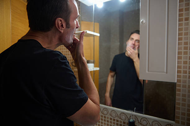 istock Man Shaving in Bathroom Mirror During Morning Routine of a Home-Working Father 2247691324