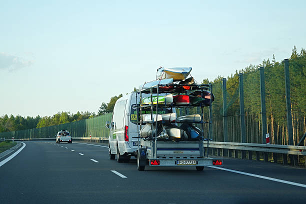 Swiebodzin, Poland - May 01.2025 A white van with a trailer carrying several kayaks or small boats on the highway