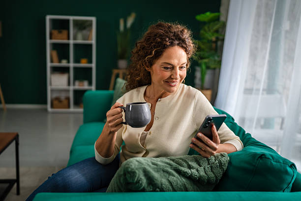 istock Mature woman relaxing at home using smart phone and drinking coffee 2247693919