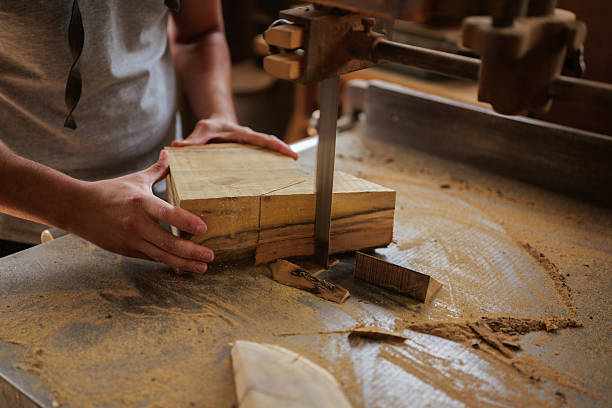 istock Carpenter carefully guiding a piece of wood through a bandsaw, creating precise cuts in a traditional woodworking workshop, surrounded by sawdust and tools 2247695888