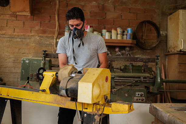 istock Young carpenter wearing a protective mask, skillfully operating a wood lathe, shaping a piece of wood in an old workshop filled with the scent of sawdust and creativity 2247696053