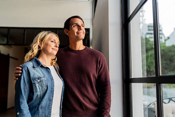 istock Happy couple looking through window at home 2247706531