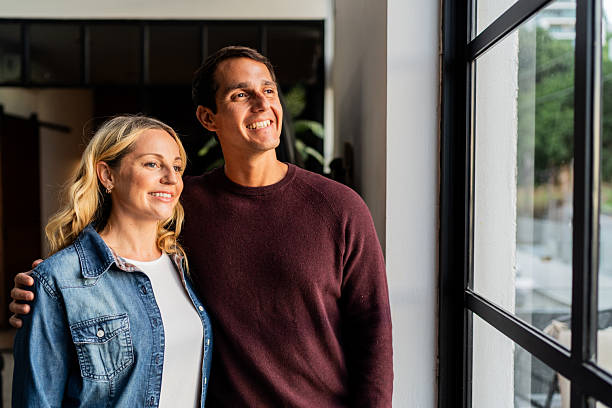 istock Happy couple looking through window at home 2247706534