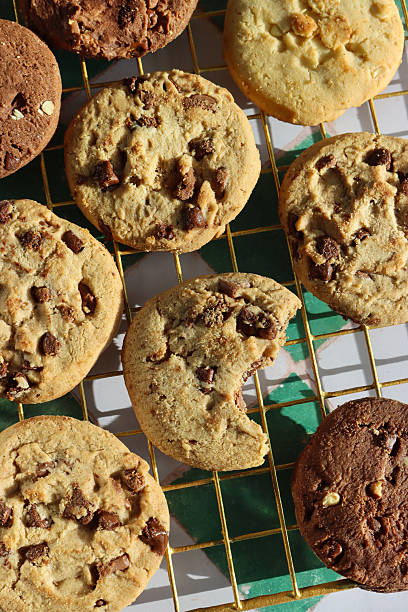 istock Full frame image of chocolate chip shortbread biscuit rounds on metal cooling rack, one missing a bite, festive holiday triple chocolate chip, milk chocolate chip and white chocolate chip cookies, white and green checked pattern background, elevated view 2247709981